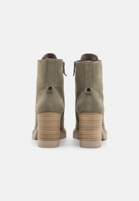 Olivengrønne ankelstøvler med en tekstureret beige hæl, med en sidelukning og dekorativ knapdetalje bagpå. Glat lædermateriale.
