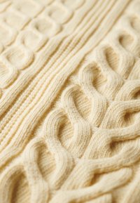 Tissu de pull en tricot jaune présentant un motif en câble textur é avec des motifs en relief et une structure de fil douce et lisse.