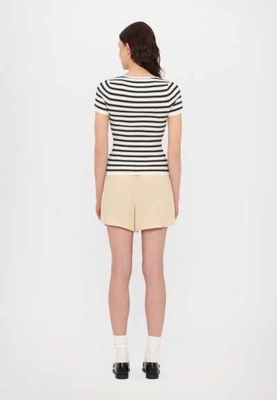 Stribet kortærmet top i sort og hvid, tætsiddende design, ribbet struktur. Sammen med beige shorts, afslappet look, simpel snit.
