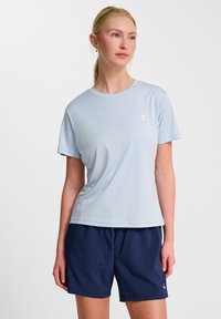 T-shirt de sport bleu clair à manches courtes, col rond et petit logo blanc sur la poitrine, associé à un short marine.
