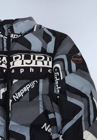 Veste noire et grise en duvet avec des motifs géométriques, arborant un logo "Napapijri", une fermeture éclair et un patch logo rond sur la manche.