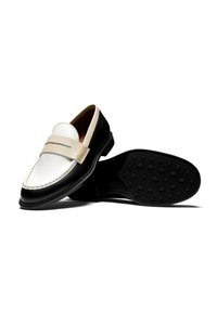 Schwarz-weiße Lederloafers mit einer glatten Oberfläche, die einen cremefarbenen Riemen über dem Blatt und eine strukturierte Gummisohle aufweisen.