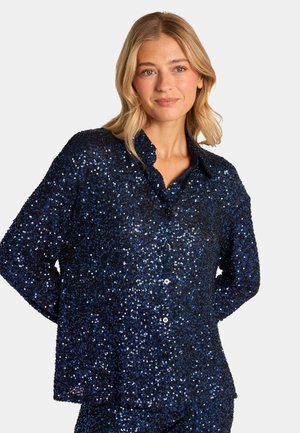Camisa de lentejuelas azul marino con cuello, mangas largas y cierre frontal de botones, que presenta una superficie texturizada y brillante.