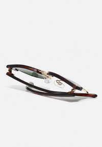 Ochelari optici din scoică de țestoasă cu accente aurii, cu suporturi de nas proeminente și un design elegant, subțire al ramelor, având lentile verzi.