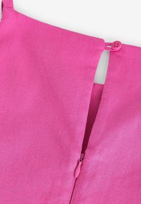 Rosa linneklänning med knappstängning och dold dragkedja. Texturen är slät med en lätt melerad look.
