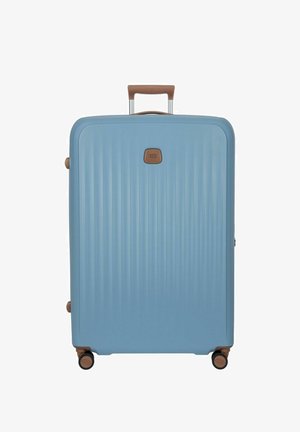 Grande valigia rigida blu con scanalature verticali, maniglie marroni e quattro ruote pivotanti nere e marroni.
