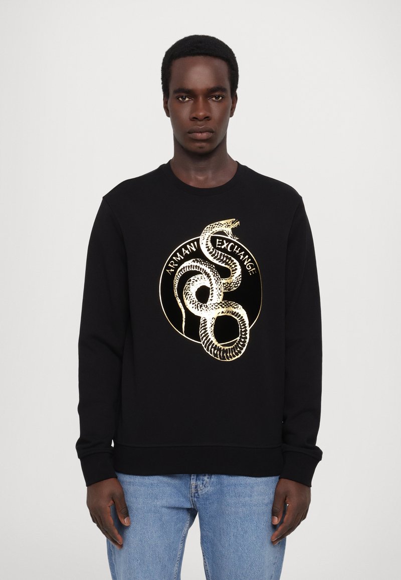 Felpa nera con grafica di un serpente dorato e testo "Armani Exchange" all'interno di un cerchio. Realizzata in un tessuto morbido e liscio con polsini a coste.