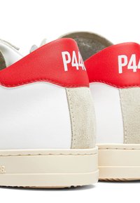 Baskets blanches avec une bande de talon en daim beige et une partie supérieure du talon rouge, avec un texte blanc "P448" sur la partie rouge.