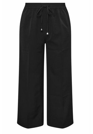 Mustat, leveälahkeiset housut, jotka on valmistettu sileästä kankaasta. Niissä on joustava vyötärö, jossa on naru ja hienovarainen kiilto. Ei näkyviä kuvioita tai taskuja.