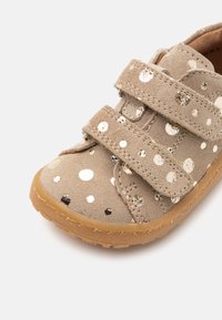 Scarpa in suede grigio con pois metallici dorati, doppie cinghie in Velcro e suola in gomma flessibile per comfort e aderenza.