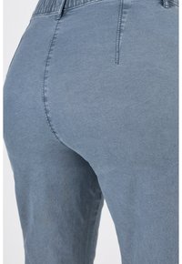 Pantaloni in denim di un morbido blu chiaro con una trama liscia. Presentano una vita elastica e dettagli cuciti lungo le cuciture.
