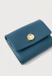 Sininen teksturoitu nahkalompakko, taitettuna kultaisella pyöreällä soljella valkoisella taustalla.