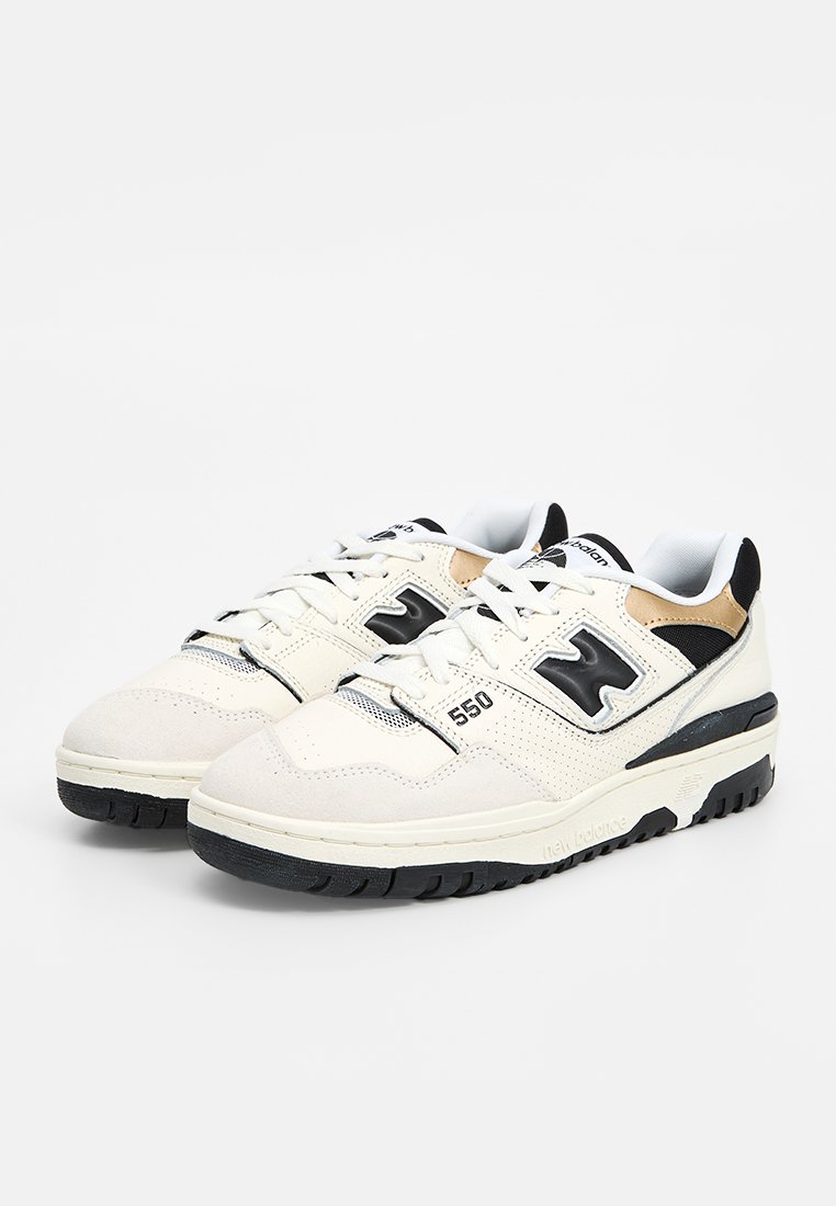 Weiße und beige Sneaker mit einem strukturierten Obermaterial aus Wildleder und Leder, schwarzen Akzenten und einer Gummisohle, die über Logo- und Modellnummerndetails verfügen.