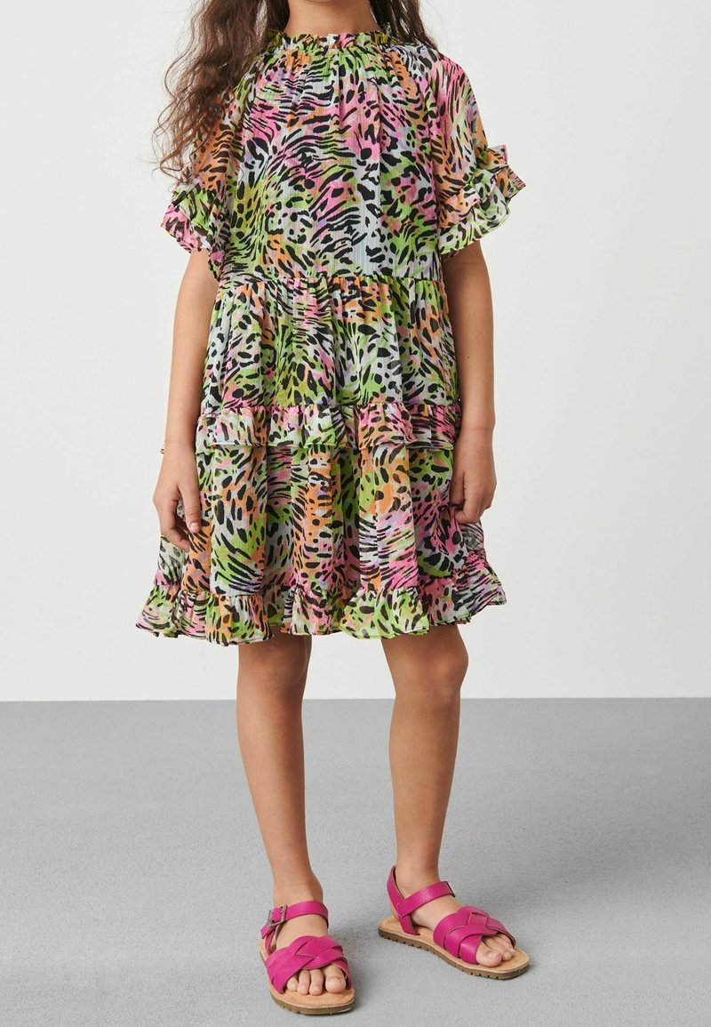 Vícebarevné šaty s výrazným zvířecím potiskem v zelené, růžové a oranžové barvě, s krátkými volány na rukávech a vrstvenou sukní. Doplněné o růžové sandály.