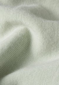 Tessuto morbido di un verde chiaro, con una fine texture a costine. La superficie presenta leggere ondulazioni, che indicano flessibilità e elasticità.