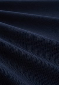 Marineblaues Stoffgewebe mit einer gerippten Struktur, das sanfte Wellen und Falten zeigt und ein Gefühl von Tiefe und Dimension erzeugt.