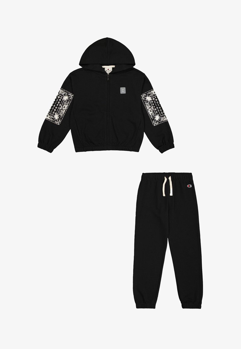 Felpa nera con zip e cappuccio, caratterizzata da dettagli bianchi a motivi sulle maniche. Pantaloni della tuta neri abbinati con vita elastica e dettaglio del logo.