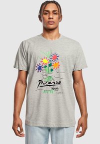 Grå bomulds t-shirt med en hånd, der holder en buket af farverige blomster. Indeholder håndskrevet tekst og et unikt kunstnerisk design.