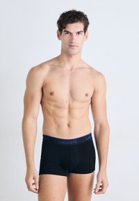Zwarte boxershorts met een fitted design en een blauw Lacoste-logo op de elastische tailleband. Zacht materiaal en naadloze constructie.