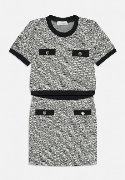 Ținută feminină din două piese cu text repetat „MONNALISA” alb-negru, finisaje negre pe mâneci, decolteu, tiv și buzunare decorative cu nasturi.