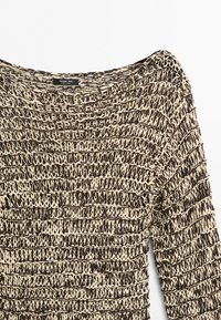 Maglione beige e marrone, a maniche lunghe, lavorato a maglia larga con punto testurizzato e scollo ampio, mostrato su sfondo semplice.