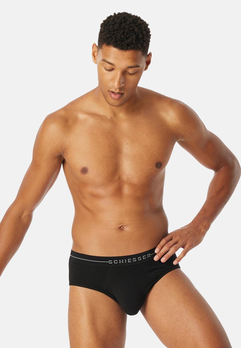 Caleçons noirs avec une ceinture grise portant le logo "SCHIESSER". Fabriqués en tissu lisse, avec une coupe ajustée sans motifs ni accents visibles.