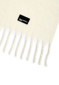 Eșarfă albă din tricot, cu margini fringed și un eticheta neagră cu textul "KARL LAGERFELD JEANS". Textură moale, design ușor.