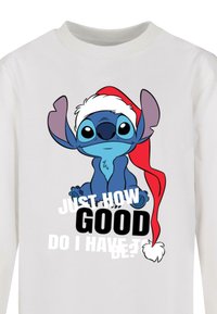 White long-sleeve shirt featuring a blue cartoon character wearing a red Santa hat, with text that reads "JUST HOW GOOD DO I HAVE TO BE?"