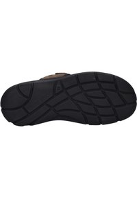 Suola in gomma nera con pattern di grip testurizzato. Presenta una parte superiore marrone con una cinghia, che fonde materiali per comfort e supporto.