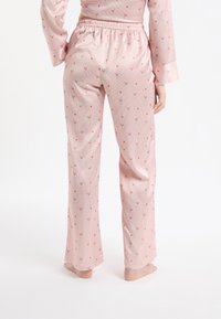 Różowy komplet piżamowy z pasiastym wzorem i kwiatowym nadrukiem. Spodnie mają elastyczną talię i są wykonane z gładkiego, miękkiego materiału.