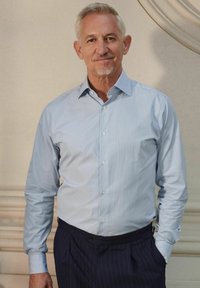 Chemise à manches longues bleu clair à rayures, avec un col ouvert, associée à un pantalon à fines rayures sombres. Texture lisse, coupe ajustée.
