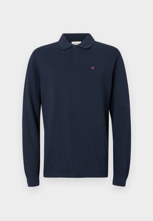 Námornícky modrá polokošela s dlhým rukávom s golierom, dvojitým gombíkovým zapínaním a malým červeným logom CK na ľavej hrudi. Bavlnená tkanina.