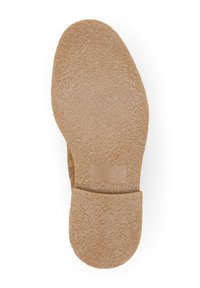 Suela de zapato color bronce con una superficie de goma texturizada. Forma contorneada con un tacón plano y un acento suave cerca del área del arco.