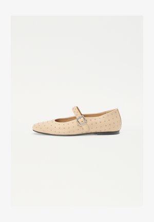 Bailarinas beige con punta redondeada, adornadas con tachuelas metálicas, con una correa lateral de hebilla y una suela plana. Textura suave.