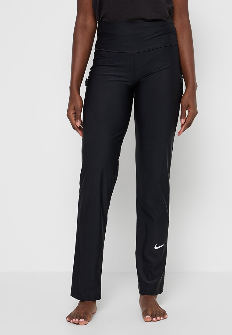 Schwarze Sporthosen verfügen über einen hohen Bund, glattes Material und ein dezentes Nike-Logo in Weiß am unteren Bein. Sie bieten ein figurnahes Design.