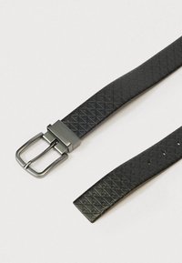 Μαύρη δερμάτινη ζώνη με υφή σε σχέδιο διαμαντιού, με κομψή μεταλλική πόρπη. Ο σχεδιασμός περιλαμβάνει τρύπες ζώνης για ρύθμιση μεγέθους.