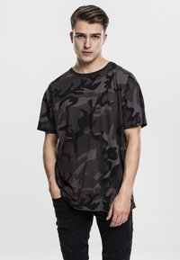 Mørk camouflage t-skjorte med avslappet passform, korte ermer og rund hals, laget av mykt stoff med glatt tekstur.