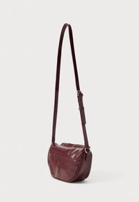 Μπορντό δερμάτινη τσάντα χιαστί με ρυθμιζόμενο λουρί. Στρογγυλεμένο σχήμα, λεία υφή και λεπτομέρεια μπροστινής τσέπης. Ιδανική για καθημερινή χρήση.