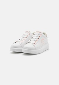 White leather sneakers with rose gold eyelets and branding. Thick rubber sole, rounded toe, and lace-up design. Simple and modern appearance.