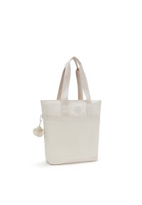 Witte tote bag gemaakt van textuurstof, met dubbele handvatten, een ronde logo en een afneembare pluizige charm. Eenvoudig ontwerp en structuur.