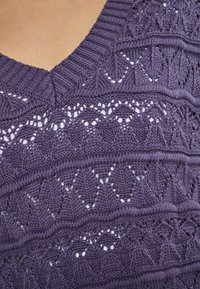 Maglione lavorato a maglia viola con un motivo testurizzato e dettagli a giorno. Design a scollo a V con bordi a coste e vari motivi di punto.