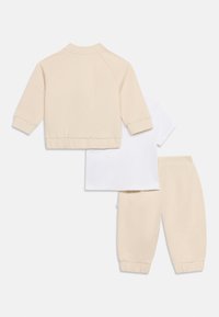 Μπεζ μακρυμάνικο σακάκι, λευκό κοντομάνικο πουκάμισο και μπεζ παντελόνι με ελαστική μέση, τοποθετημένα επίπεδα σε λευκό φόντο.