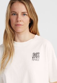 Crème-kleurige katoenen t-shirt met ronde hals en korte mouwen, met een grafische print aan de linkerkant met de tekst "O'Neill Frozen Wave."