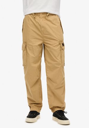 Beige Cargo-Hosen mit elastischem Bund, Seitentaschen und gerafften Bündchen. Hergestellt aus leichtem Stoff und mit einem schlichten Design.