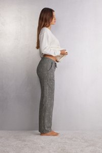 Grijze geblokte broek met zwart-wit patroon, voorzien van een trekkoord in de taille, relaxte pasvorm en zijzakken. Gecombineerd met een witte gebreide top.