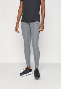 Γκρι κολάν με στενή εφαρμογή και ορατές ραφές, συνδυασμένο με μαύρο κοντομάνικο πουκάμισο και μαύρα αθλητικά παπούτσια.