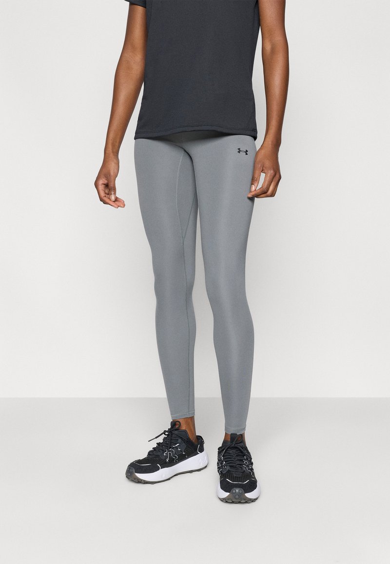 Γκρι κολάν με στενή εφαρμογή και ορατές ραφές, συνδυασμένο με μαύρο κοντομάνικο πουκάμισο και μαύρα αθλητικά παπούτσια.