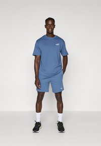 Blue athletic T-shirt and shorts set, featuring logo accents, regular fit, and smooth texture, paired with black athletic shoes and white socks.