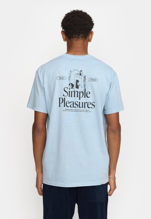 Helles blaues Baumwoll-T-Shirt mit einem bedruckten Grafikdesign auf der Rückseite, das "Einfache Freuden", Kopfhörer und eine Illustration eines Retro-Geräts zeigt.