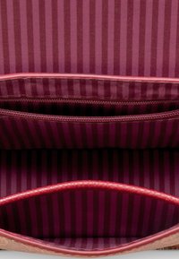 Roter Handtascheninnenraum mit vertikalen dunkelrosa und hellrosa Streifen, einschließlich einer Reißverschlusstasche und verstärkten Kanten.